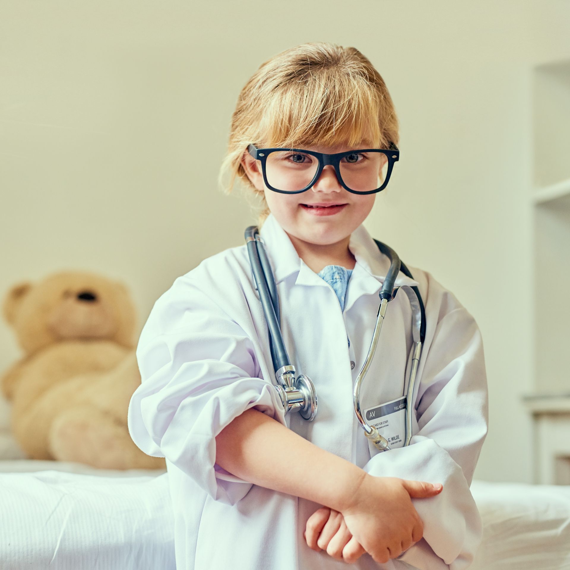 Little girl dressed up as a pediatrician with a teddy bear as her patient
