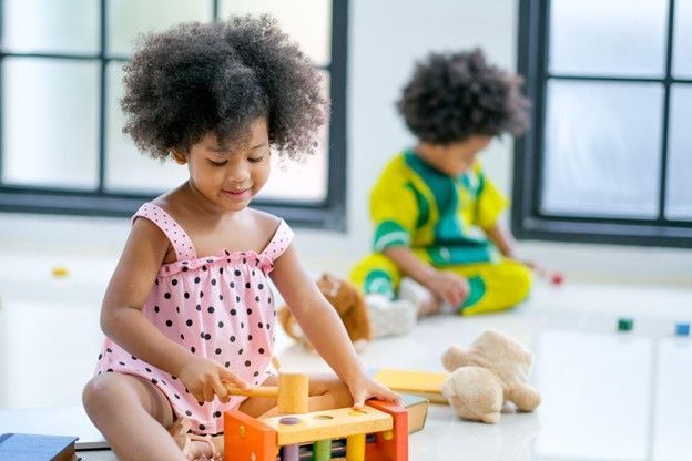A little girl is sitting on the floor playing with toys.