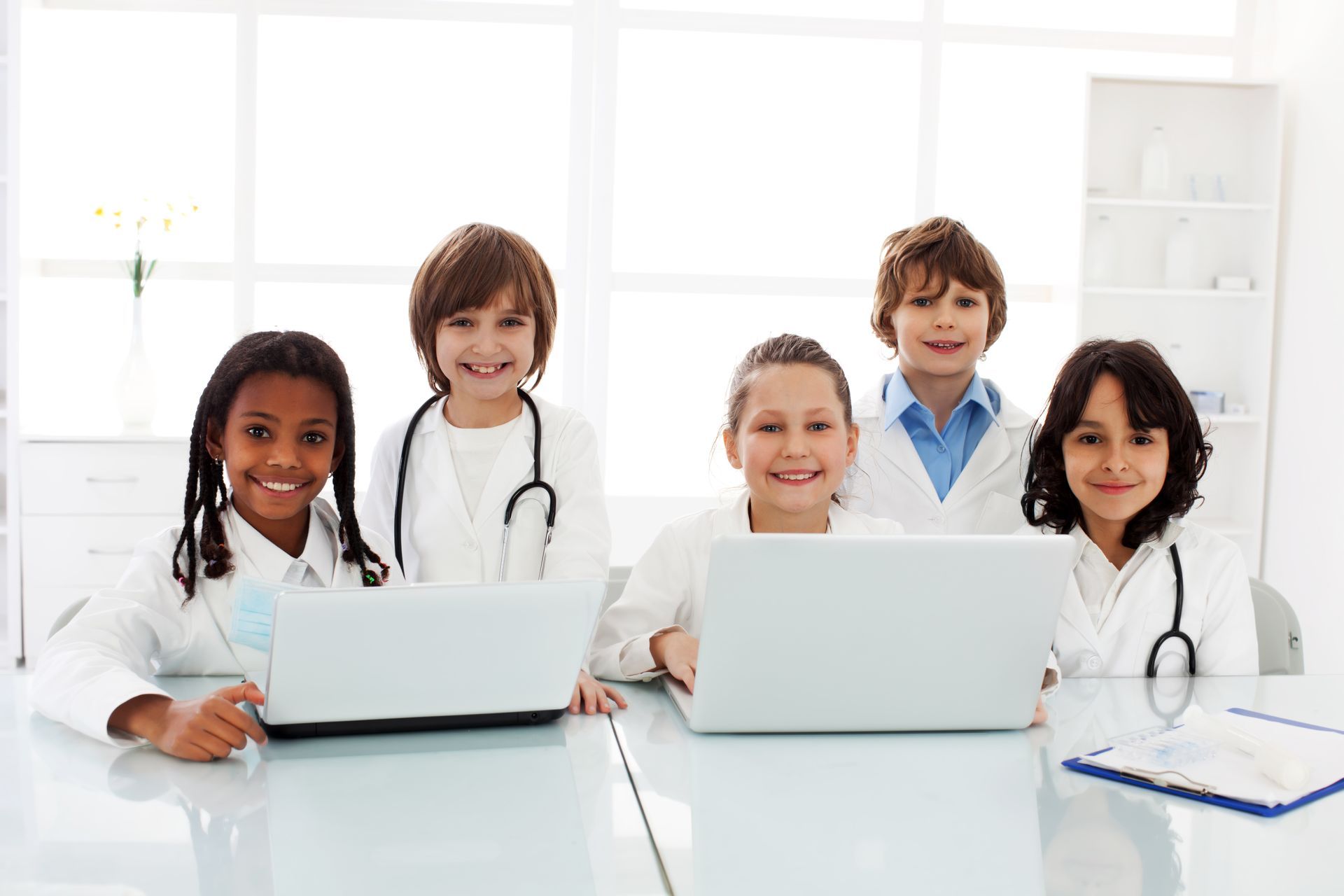 Smiling group of children dressed as pediatricians with computers