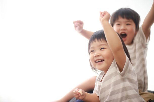 Two Asian boys cheering with arms in the air
