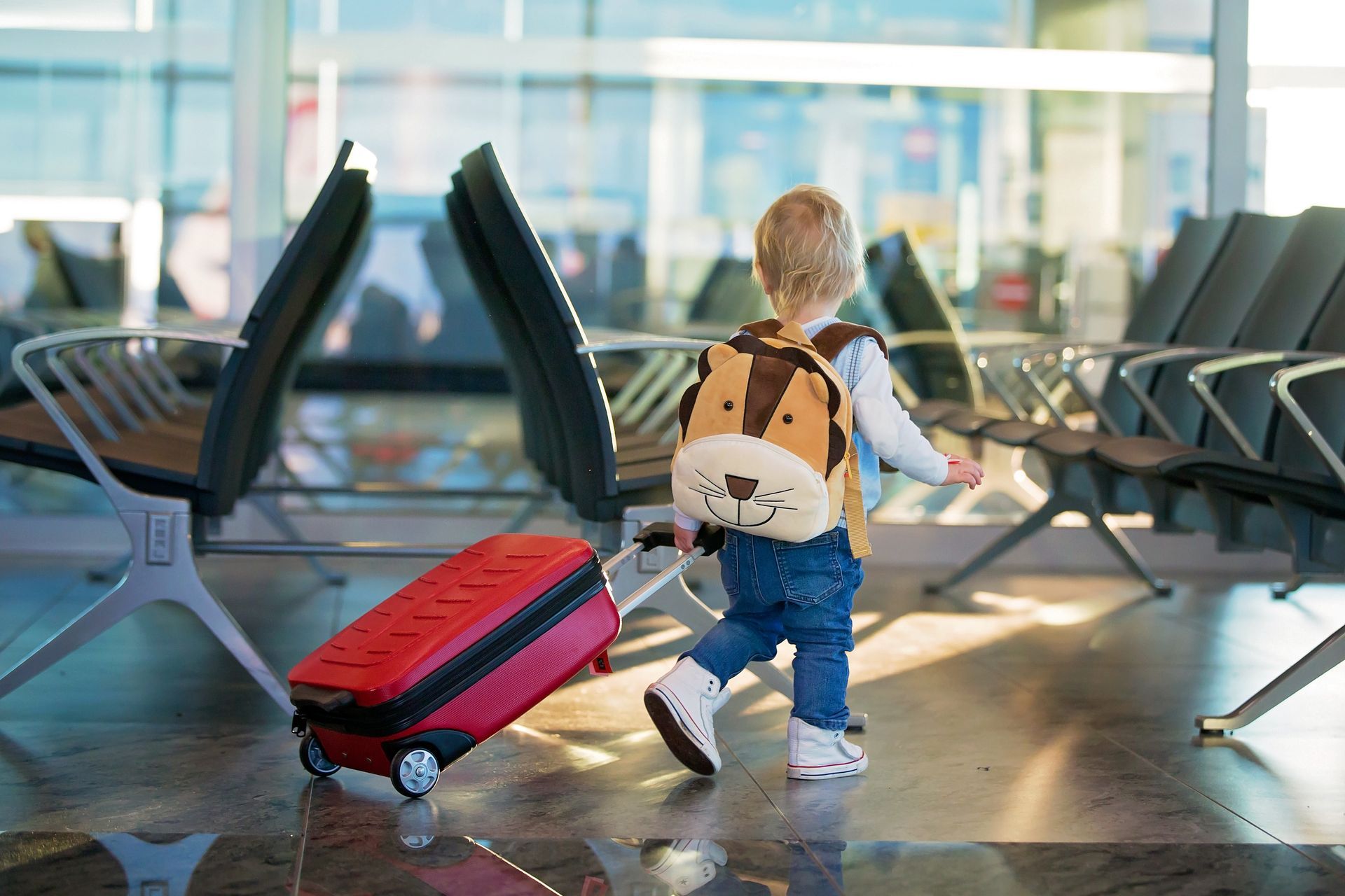 A little boy is pulling a suitcase at the airport.