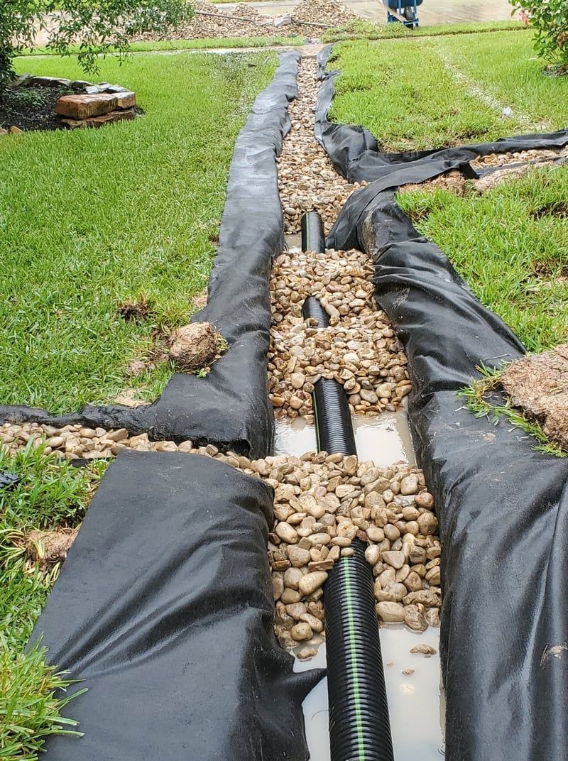French drain installed in the backyard, black drain pipe covered with stones