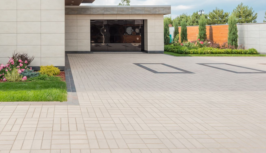 Modern house driveway with paved courtyard, open garage, and landscaped garden in front