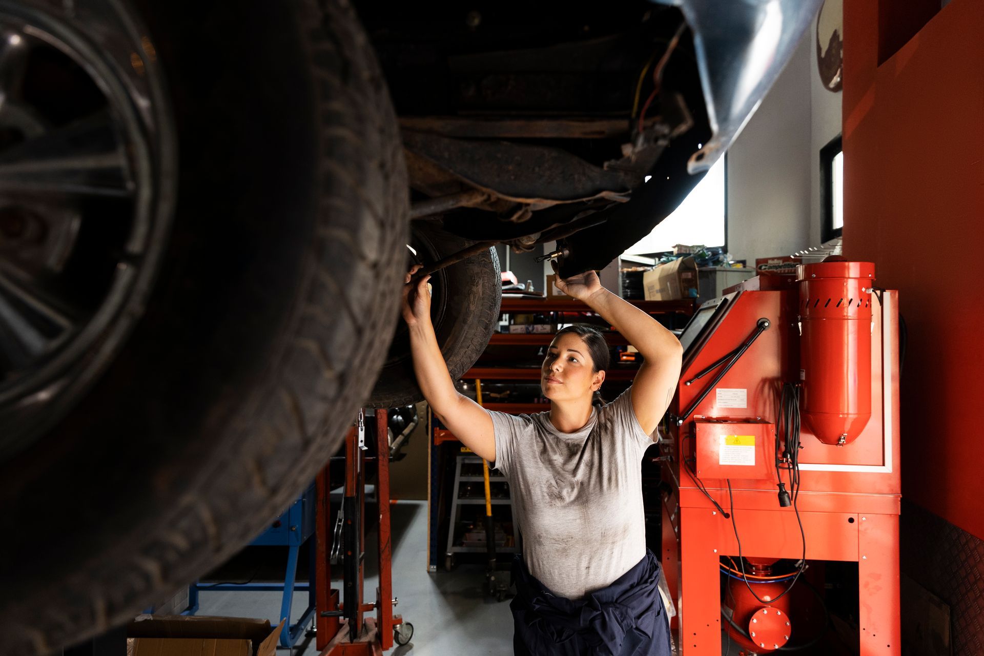 Mechanic inspecting the underside of a car in an auto repair shop