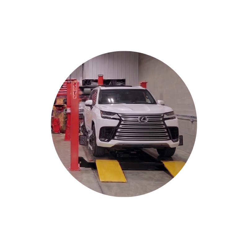 White Lexus SUV positioned on professional wheel alignment equipment inside a service facility.