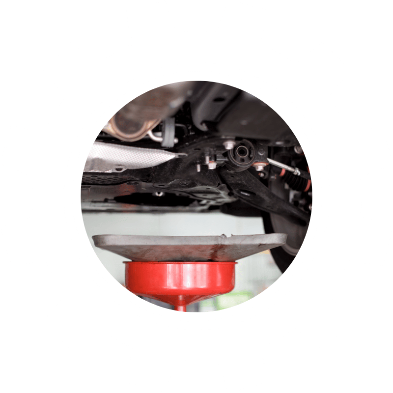 Vehicle raised on a lift with a drain pan positioned underneath during a routine engine oil and filter change service.