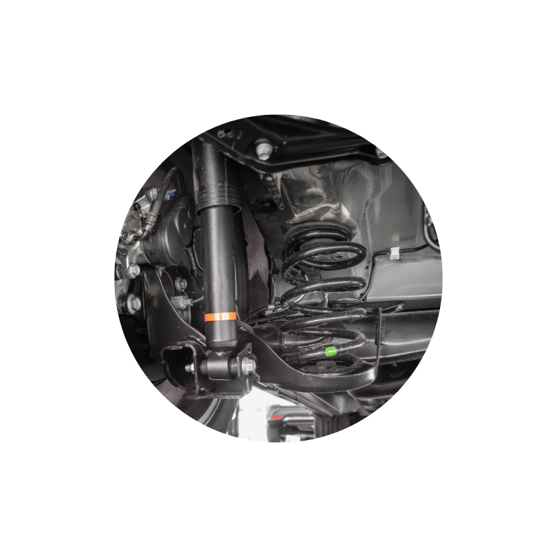 Close-up of a vehicle suspension system showing the shock absorber and coil spring components during inspection or repair.