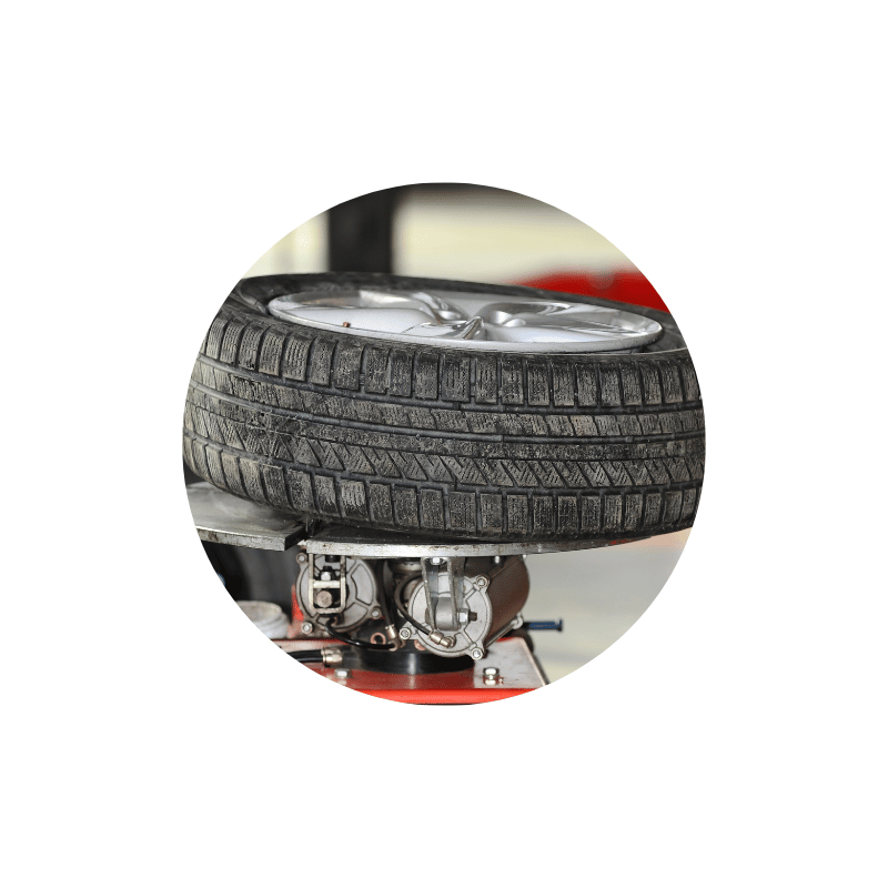 Vehicle tire mounted on a tire service machine, representing tire rotation, balancing, and maintenance services.
