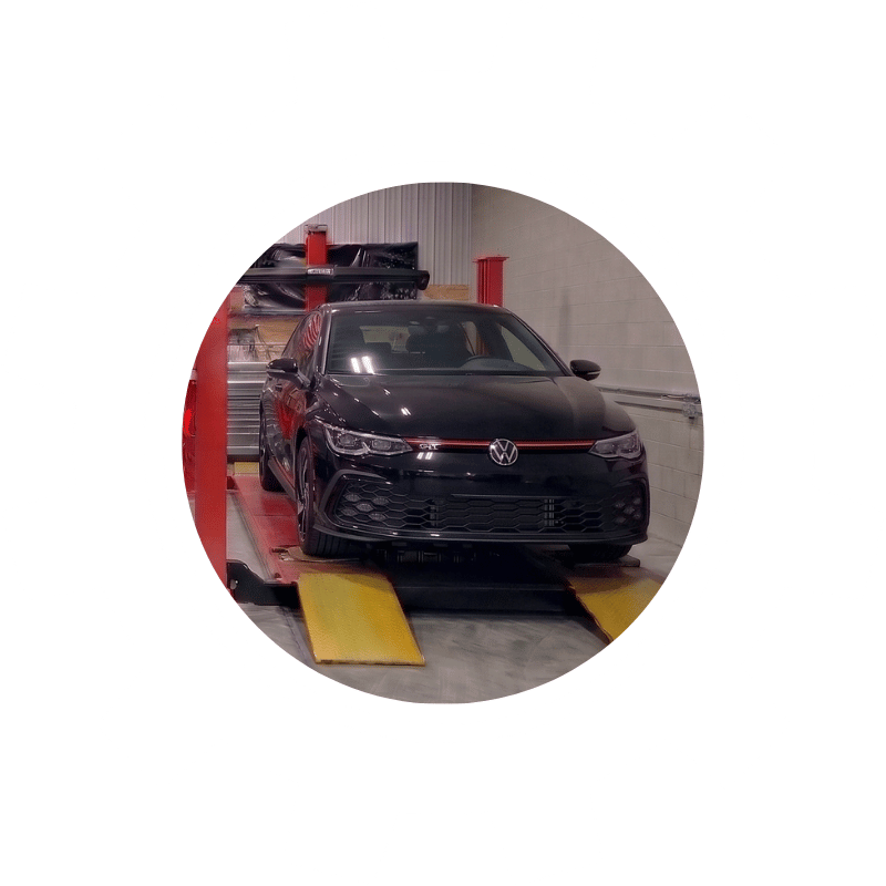 Black Volkswagen sedan undergoing wheel alignment service to enhance steering response and tire performance.