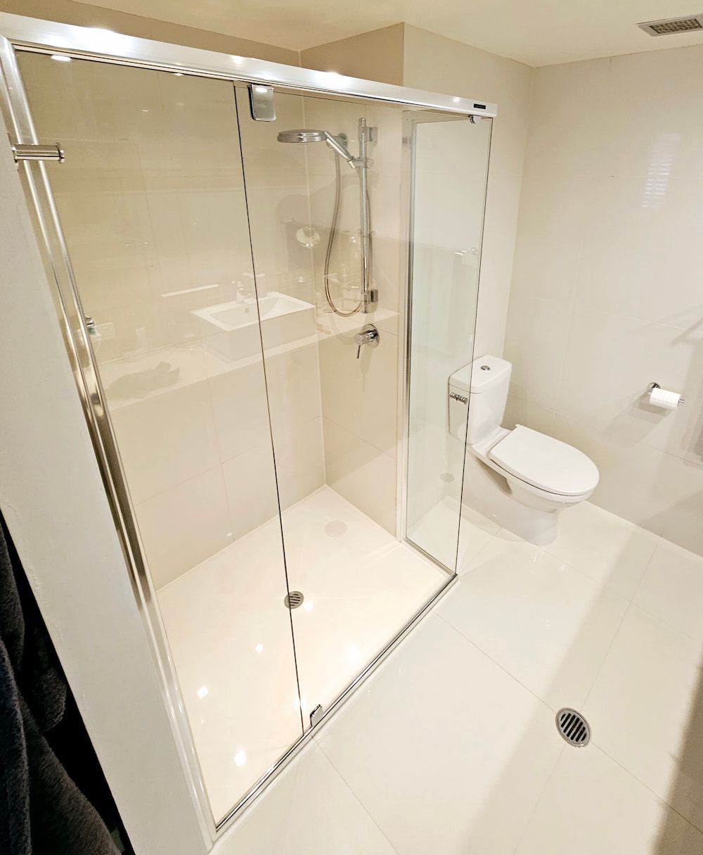 A Bathroom With A Toilet And Shower With Sliding Glass — Mobile Shower Door Doctor In Mountain Creek, QLD
