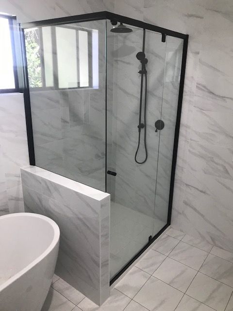 A Bathroom With A Bathtub And A Shower Stall With A Black Frame — Mobile Shower Door Doctor In Mountain Creek, QLD