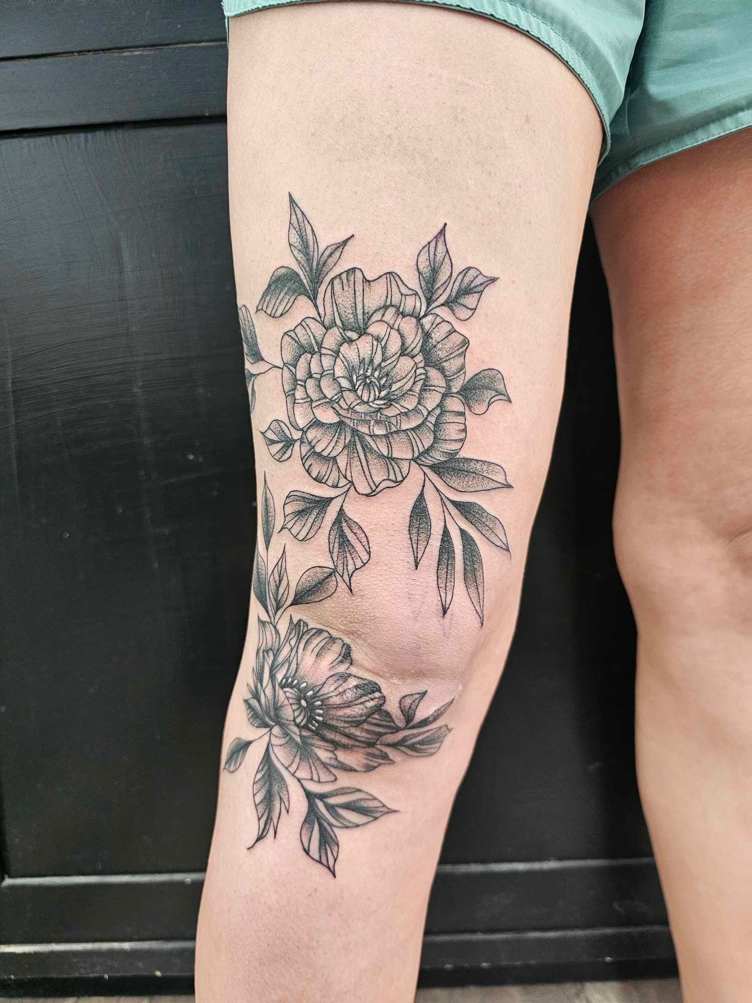 A woman has a tattoo of flowers on her knee.