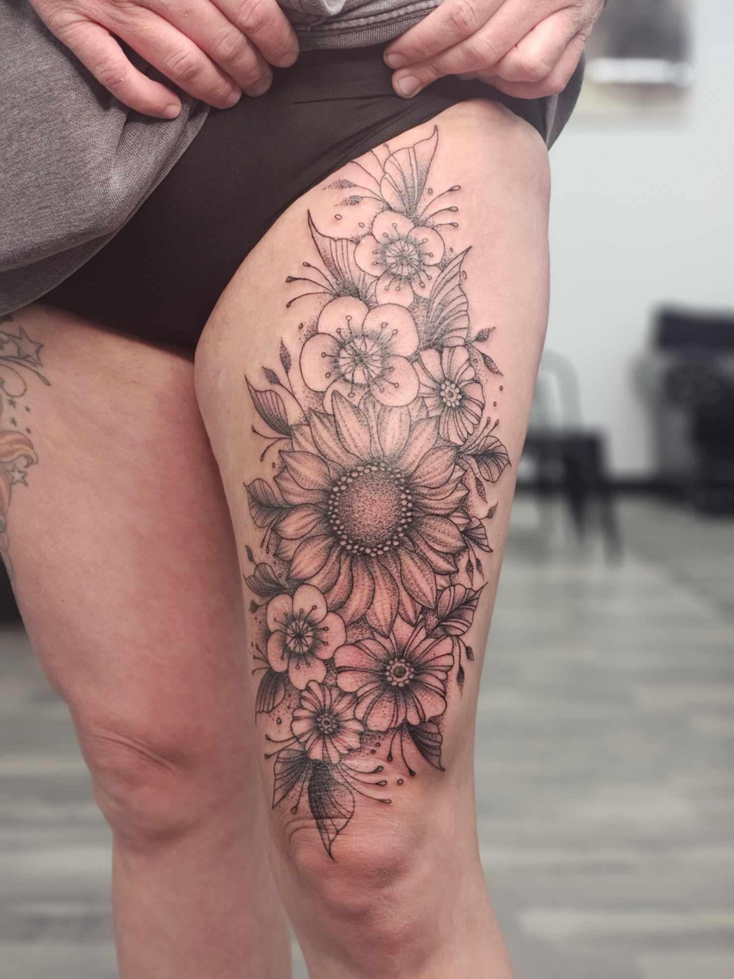 A woman has a tattoo of flowers and butterflies on her thigh.