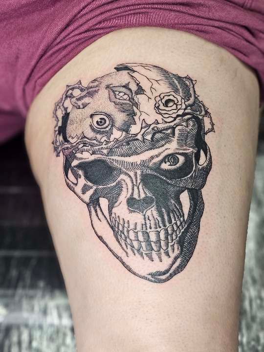 A black and white tattoo of a skull on a person 's leg