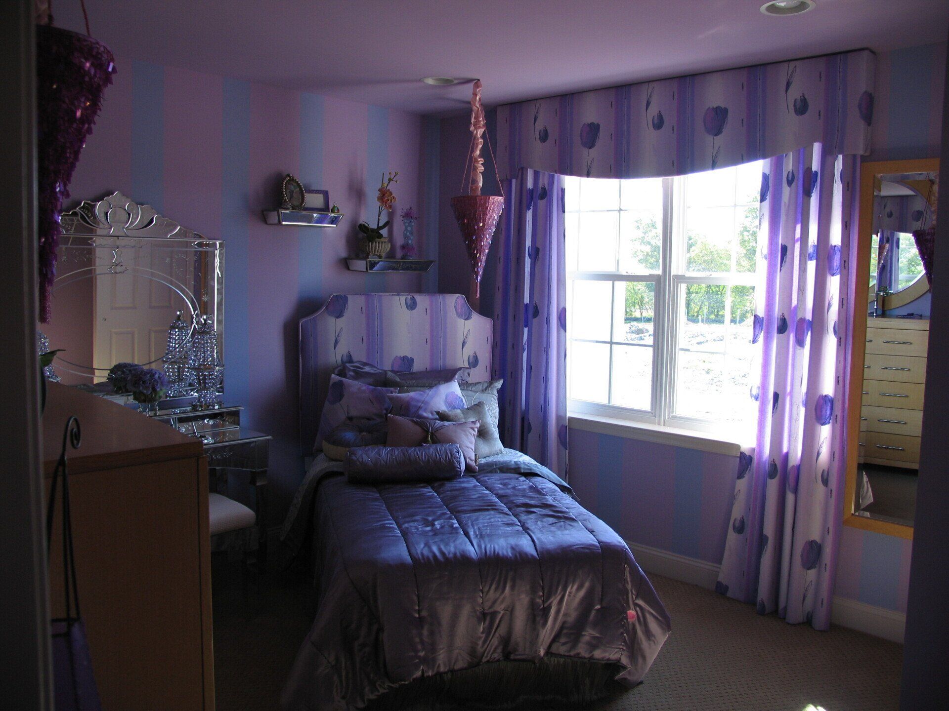 Purple bedroom with a bed, window, and dresser.