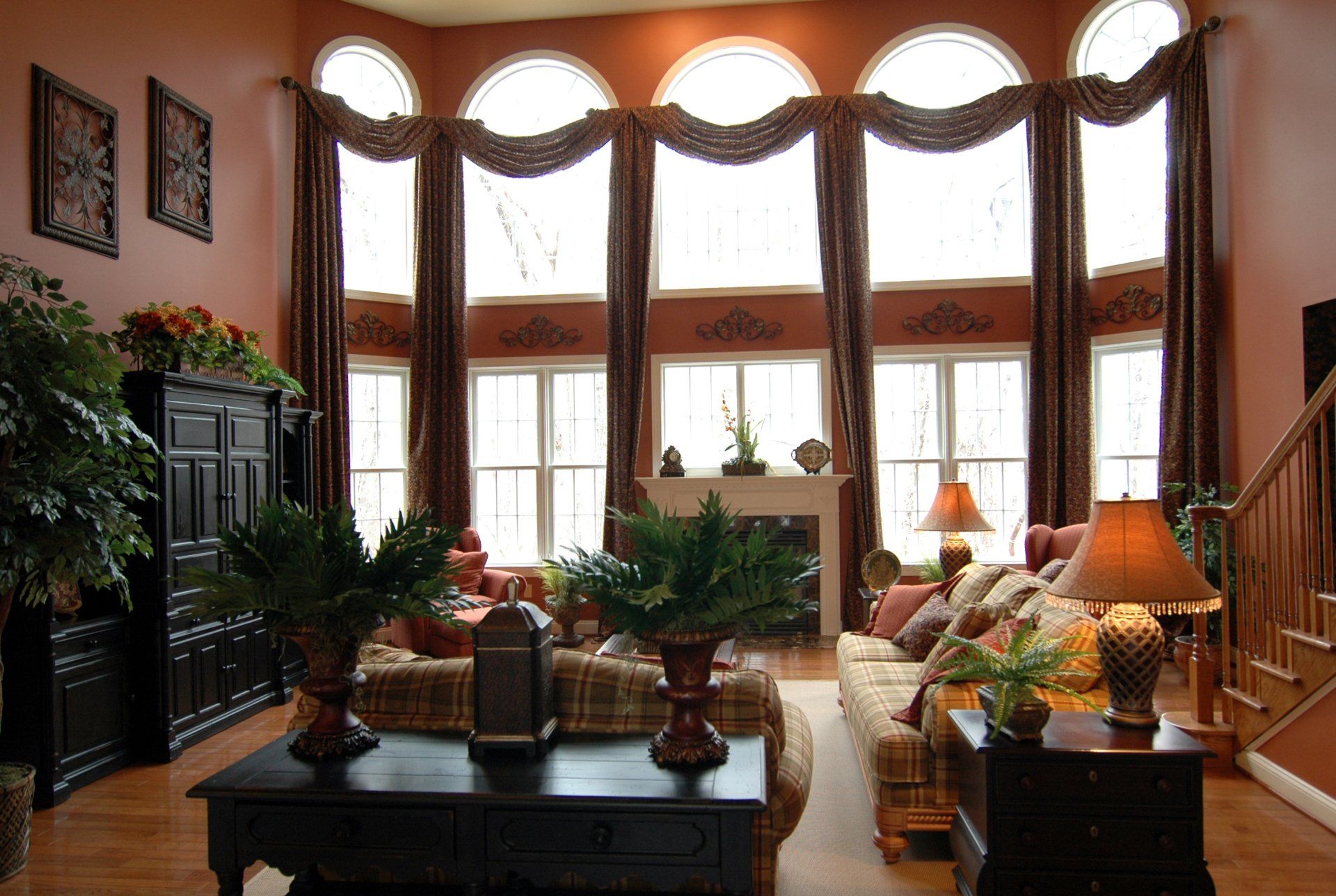 Living room with tall windows, brown curtains, fireplace, and furniture.