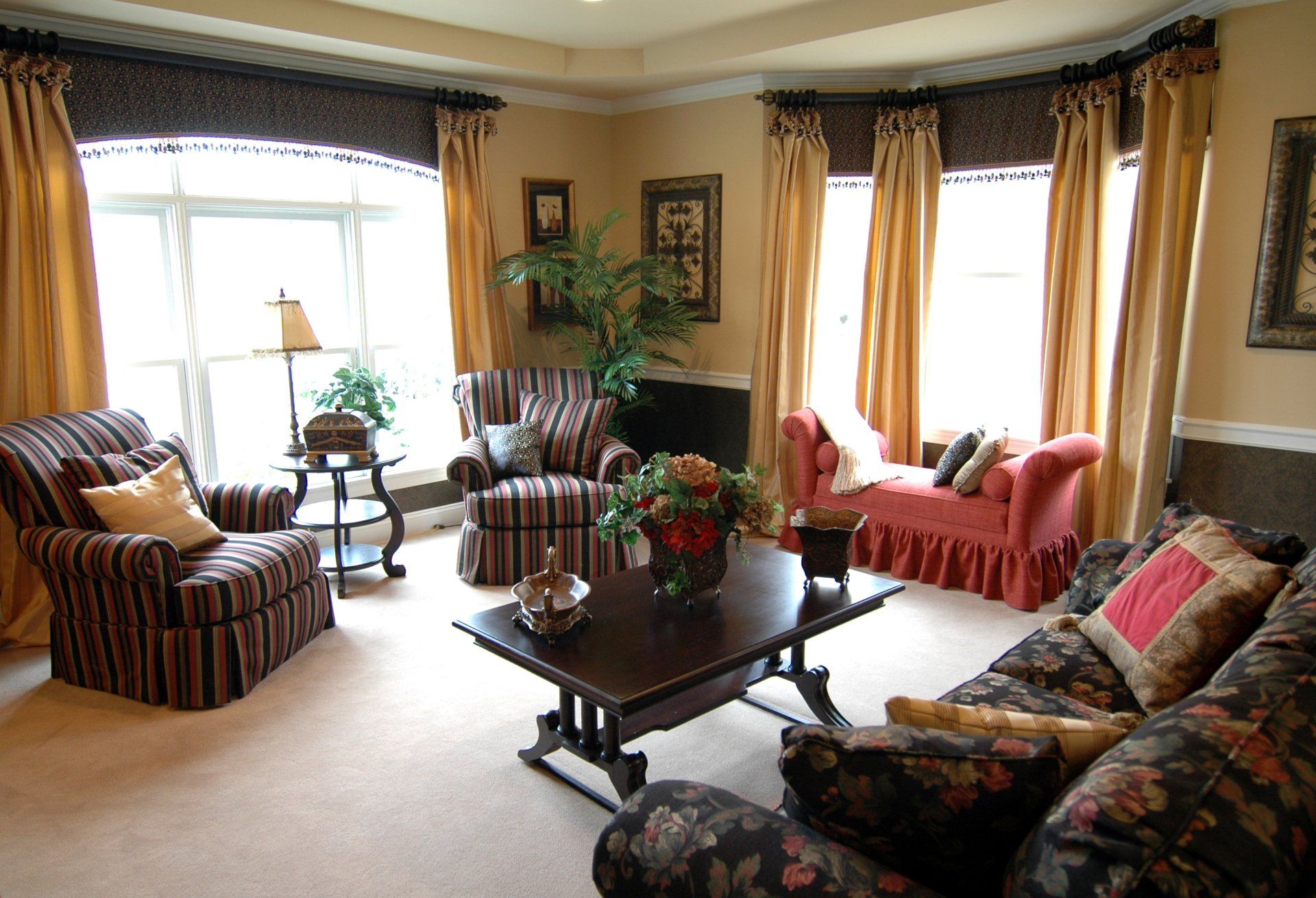 Living room with patterned furniture, gold curtains, and a dark wood coffee table.
