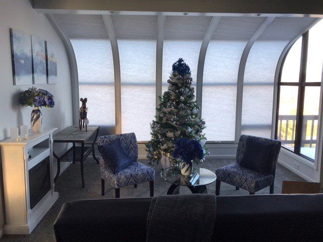 Living room with Christmas tree, blue accents, arched windows, and a fireplace.