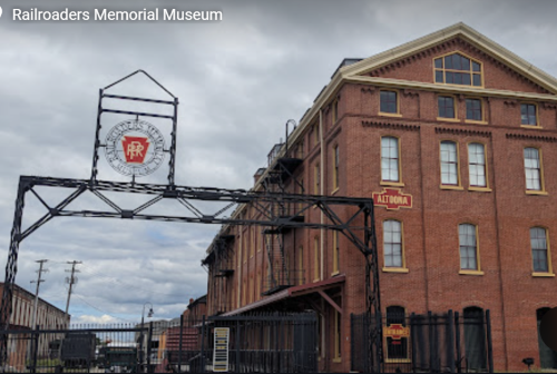 Railroaders Memorial Museum with brick building and metal entrance, Pennsylvania flag, overcast sky.