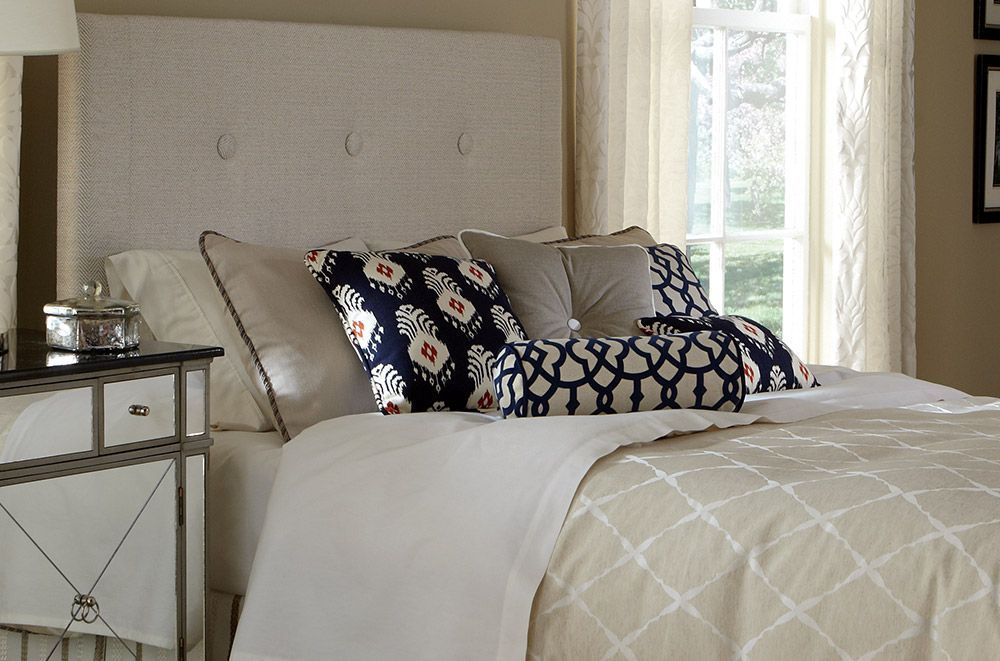 a bed with white sheets and blue and white pillows