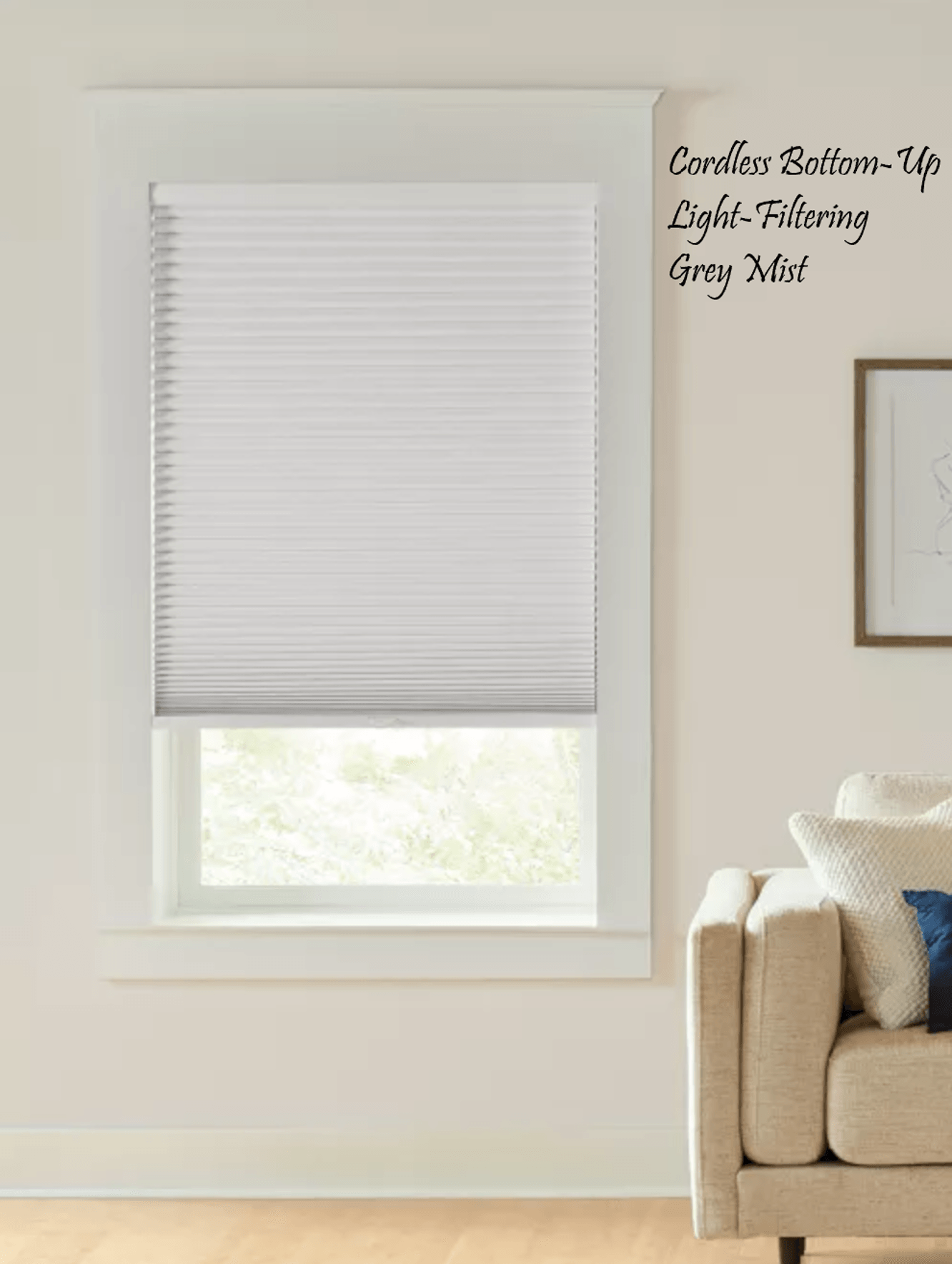 White pleated blinds, covering the top part of a window. Light-colored room with a couch and framed artwork.