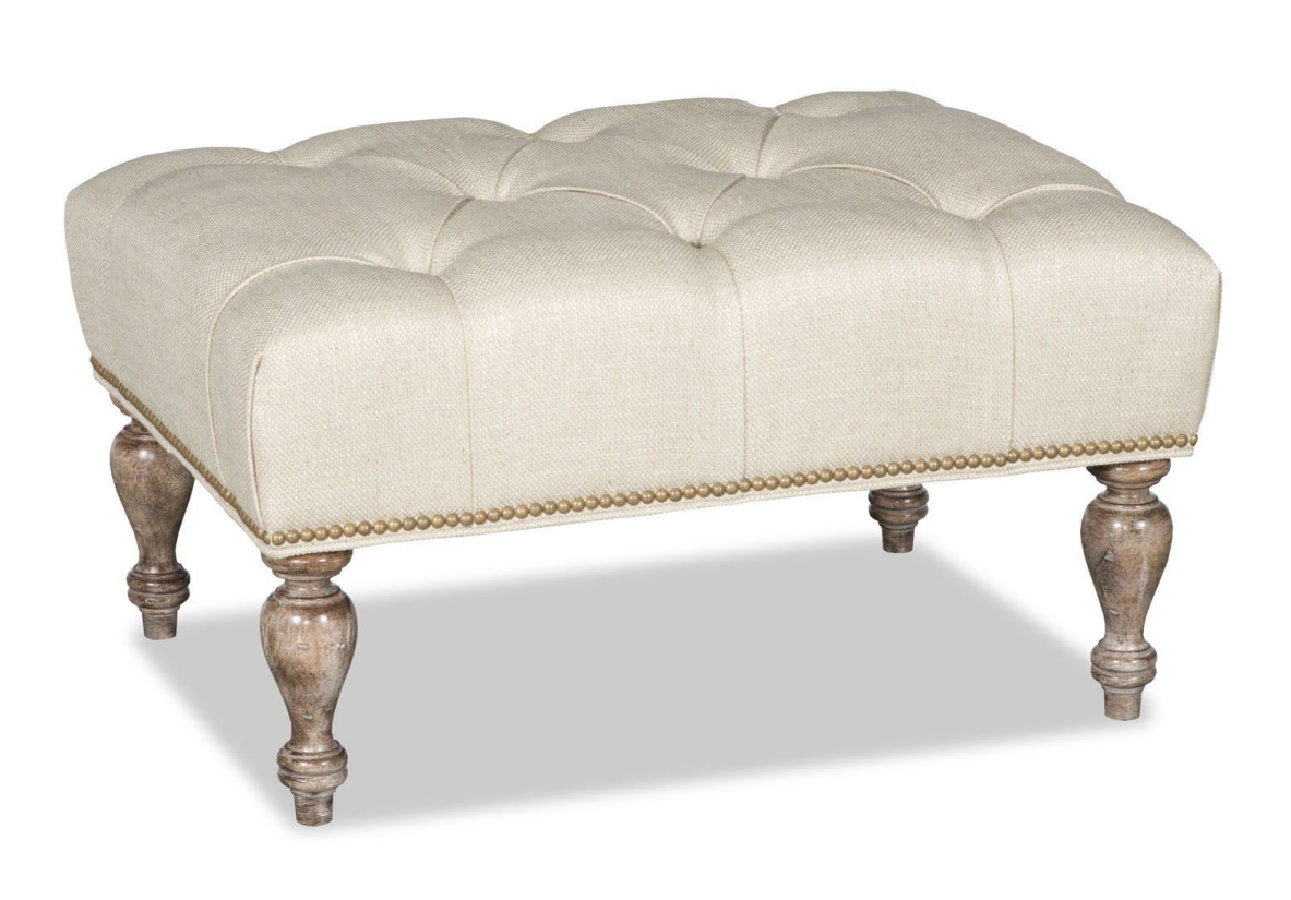 Cream tufted ottoman with wood legs, sitting on a white surface.