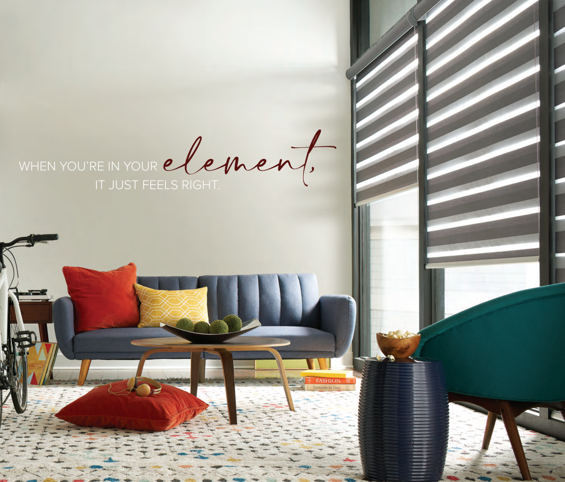 Modern living room with blue sofa, patterned rug, and striped window shades. Text on wall: