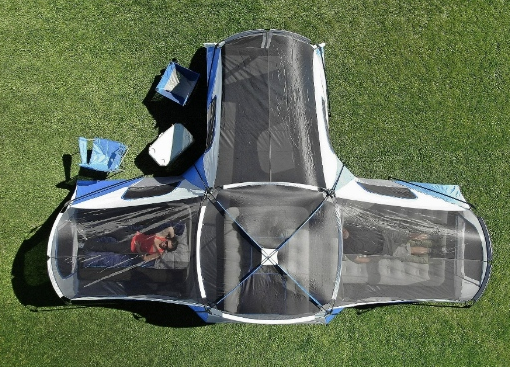 Overhead view of a blue, black, and white pop-up tent set up on green grass.