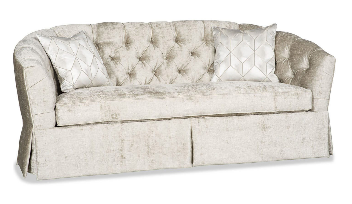 Cream-colored tufted sofa with two geometric patterned pillows.