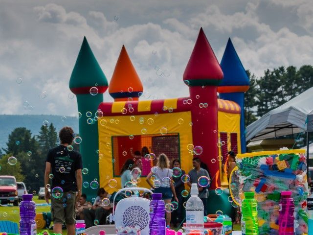 Colorful inflatable bounce house with children playing at an outdoor festival under cloudy skies