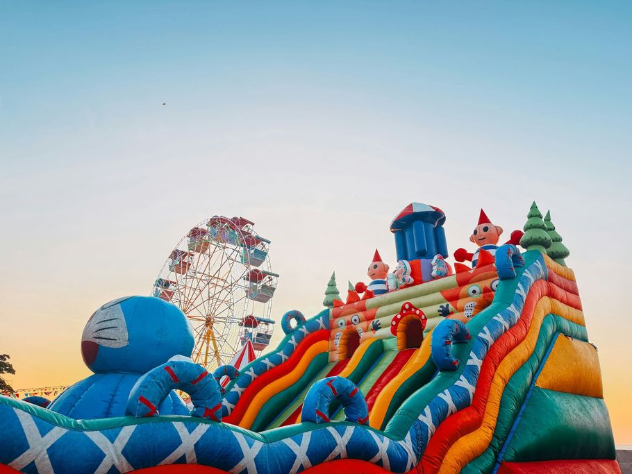 Colorful inflatable slide at an amusement park with a Ferris wheel in the background