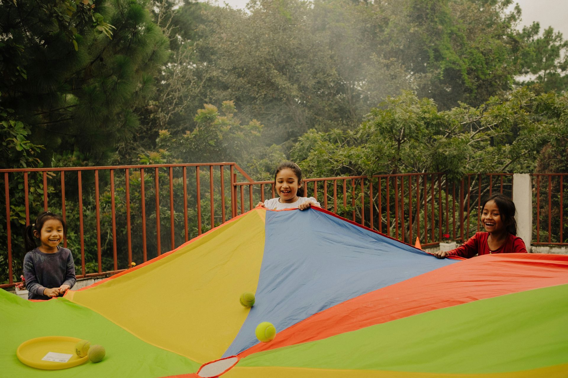 Children playing with a colorful parachute outdoors in a park