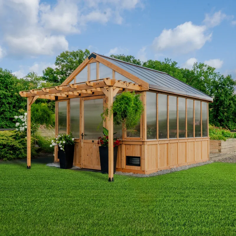 Wooden greenhouse with pergola in a grassy yard, under a cloudy sky.