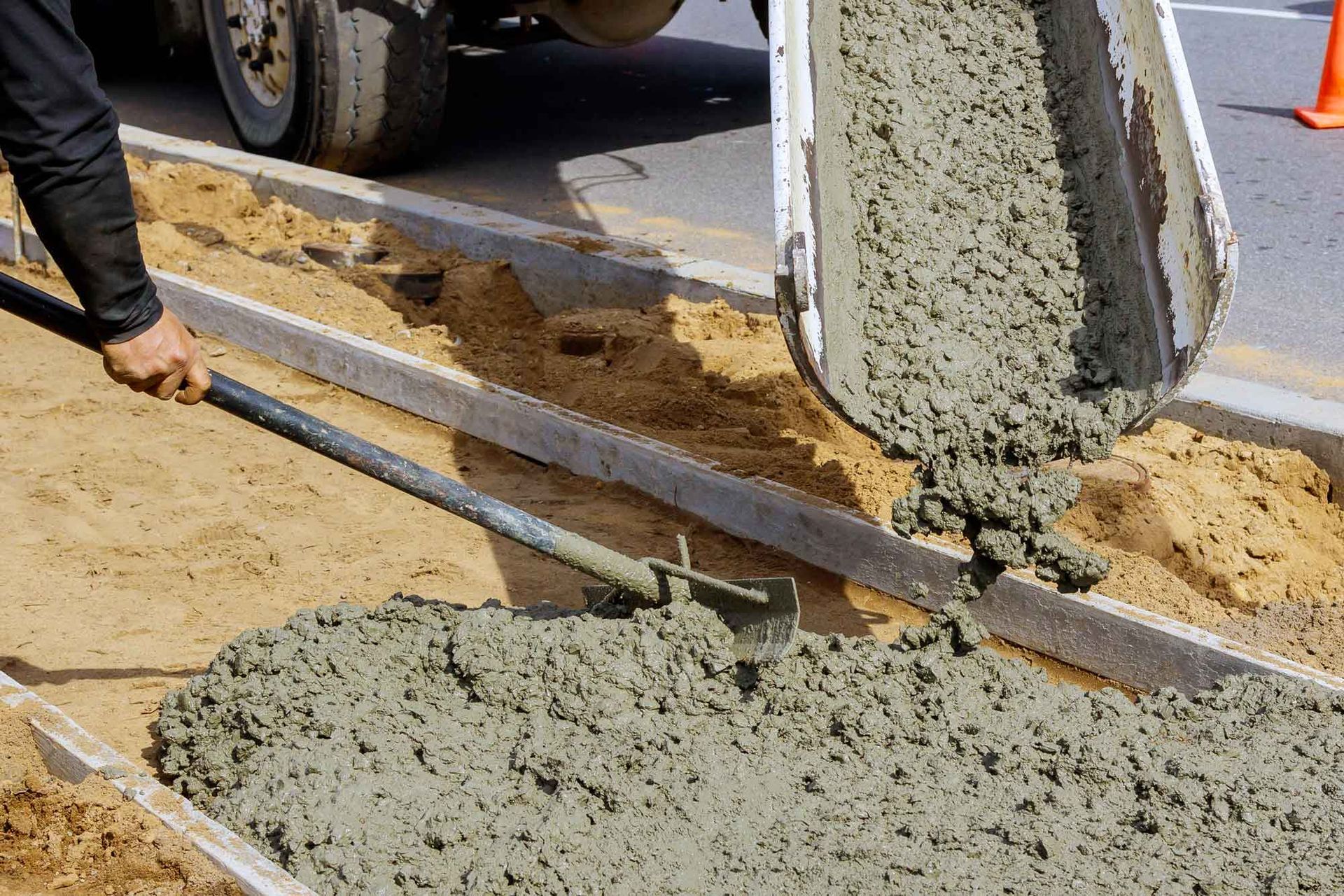 Concrete being poured into a form; worker using a shovel.