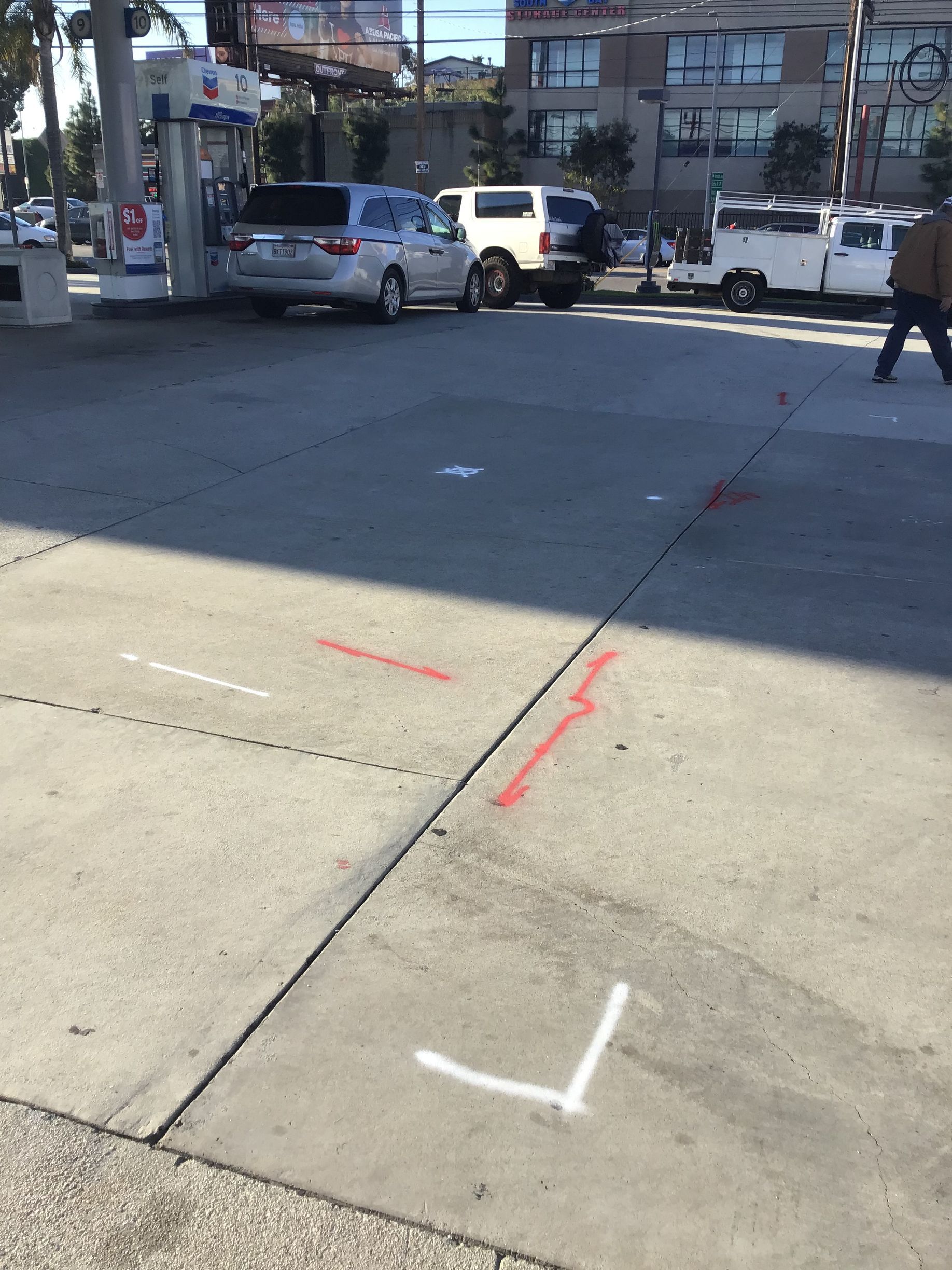 Gas station pavement with painted lines and parked vehicles.