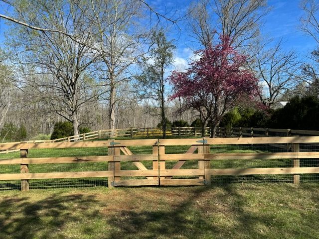 A wooden fence with a gate in the middle of a grassy field — Scottsville, Va — Pbr Grounds Llc