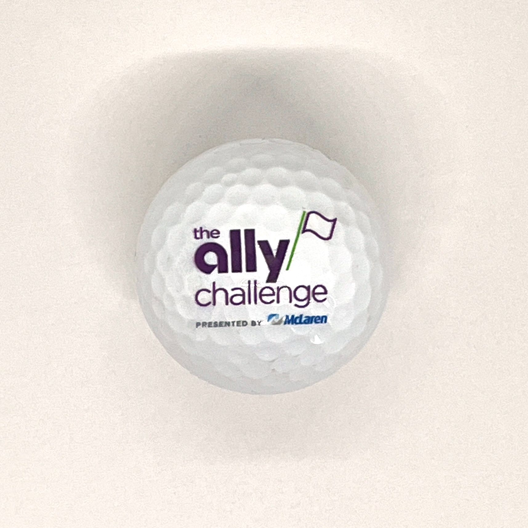 White golf ball with “the ally challenge” logo and flag icon on a light background