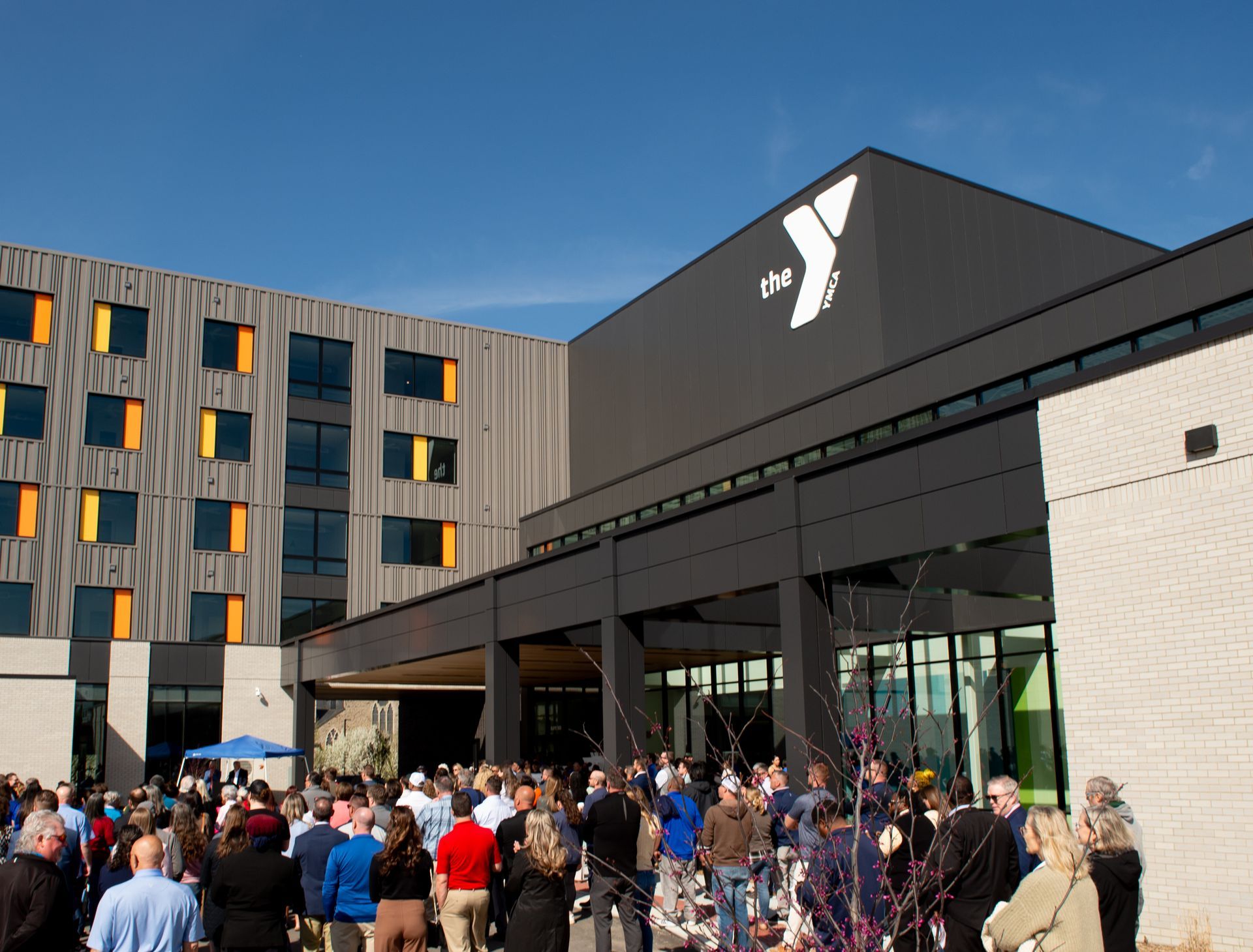 A large group of people are gathered in front of a large building with the letter y on it