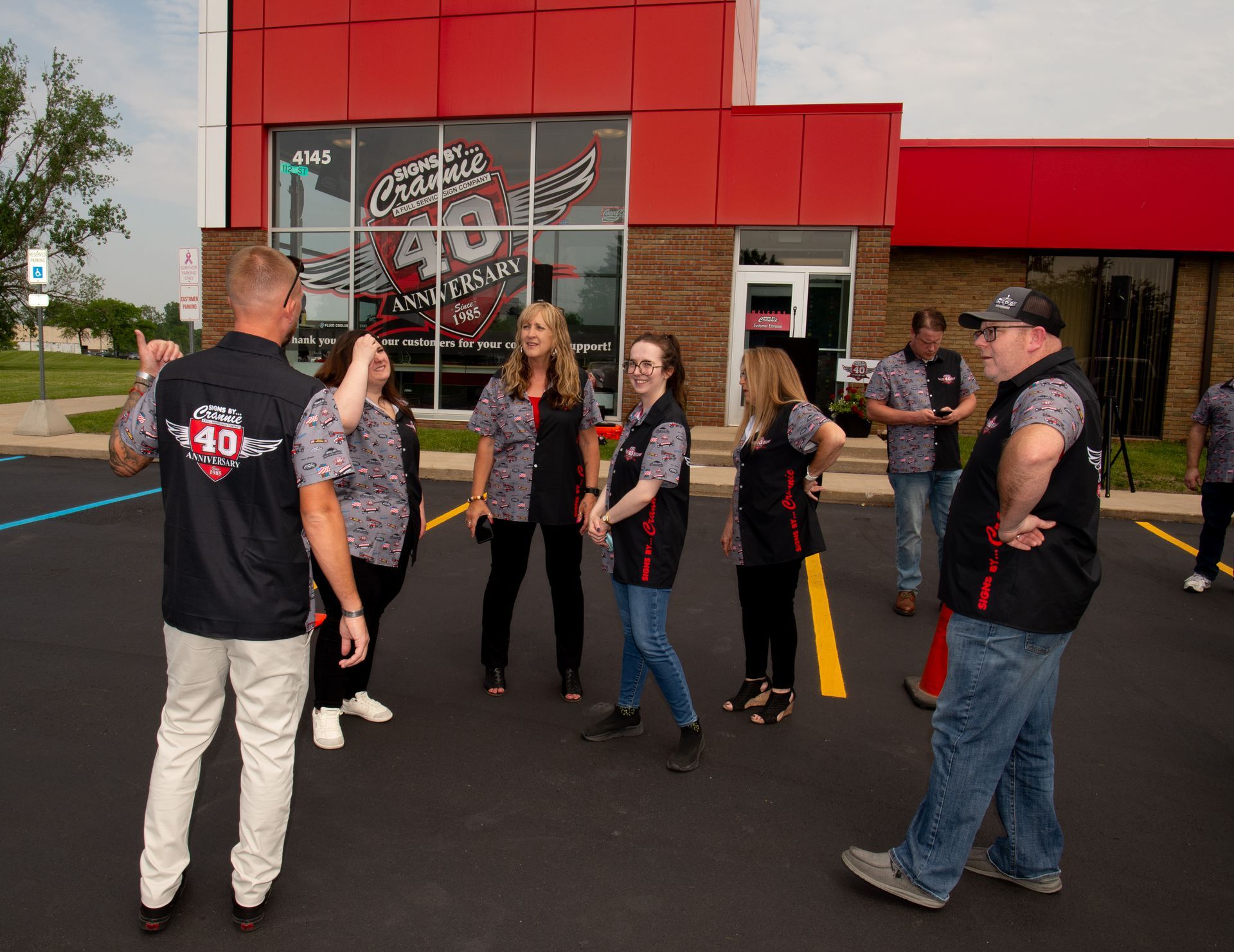 A group of people are standing in front of a red building.