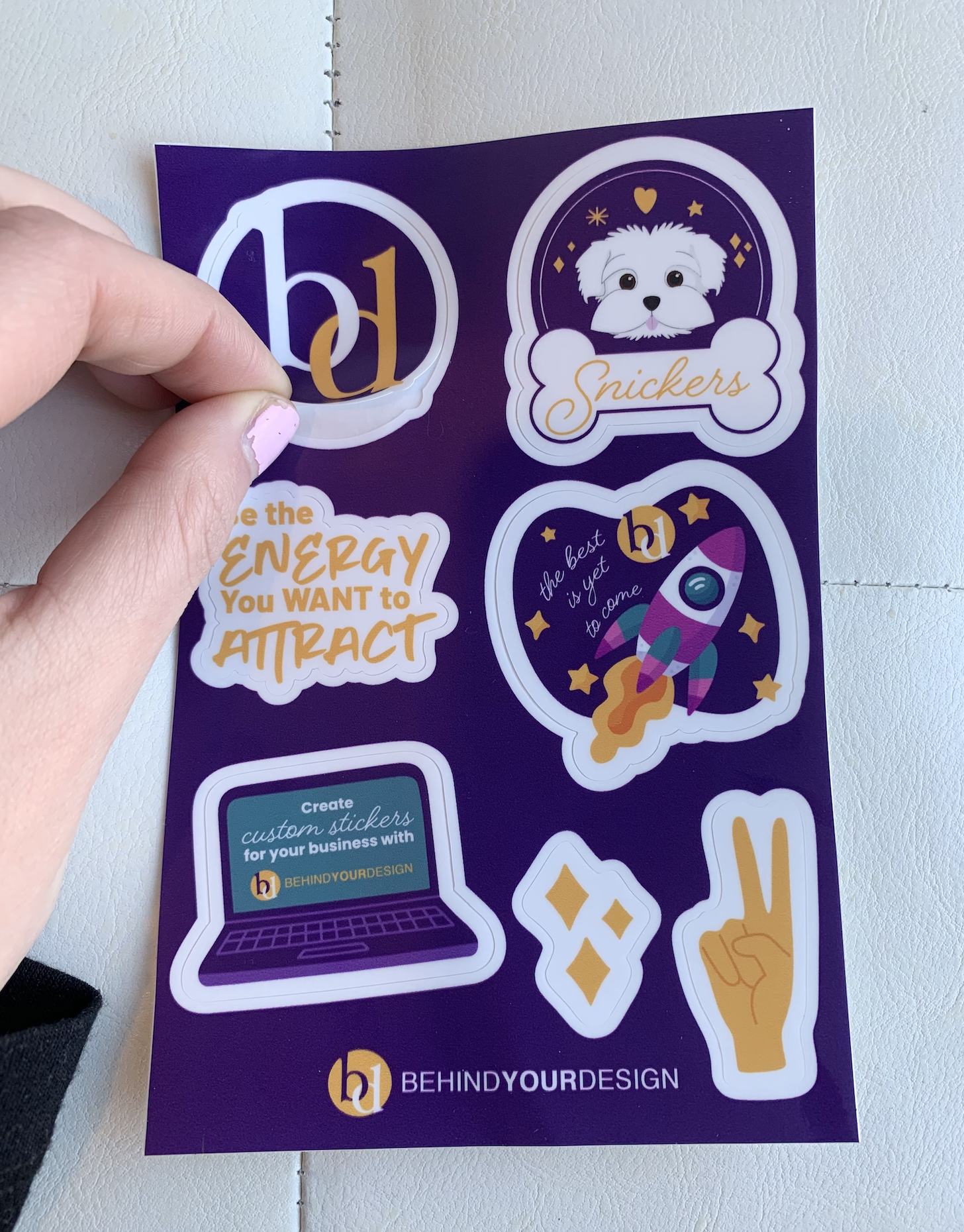 A person is holding a purple sticker that says the energy you want to attract