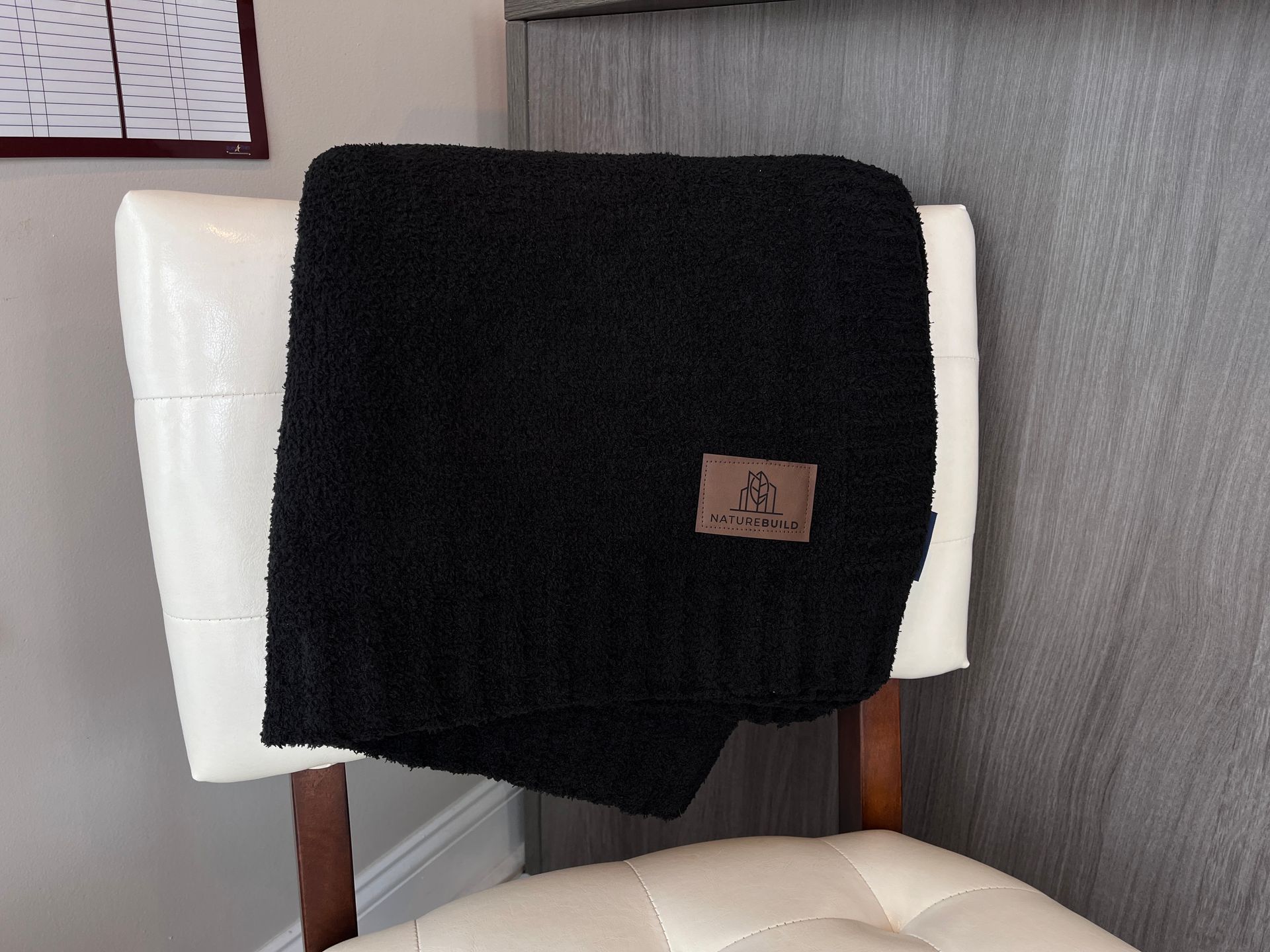 A black blanket is sitting on a white chair