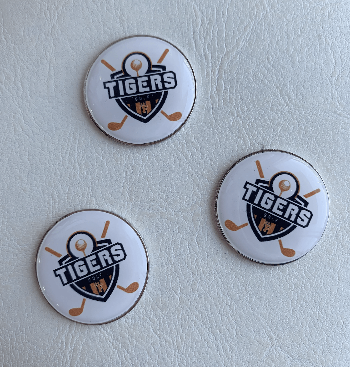 Three tigers buttons are sitting on a white surface