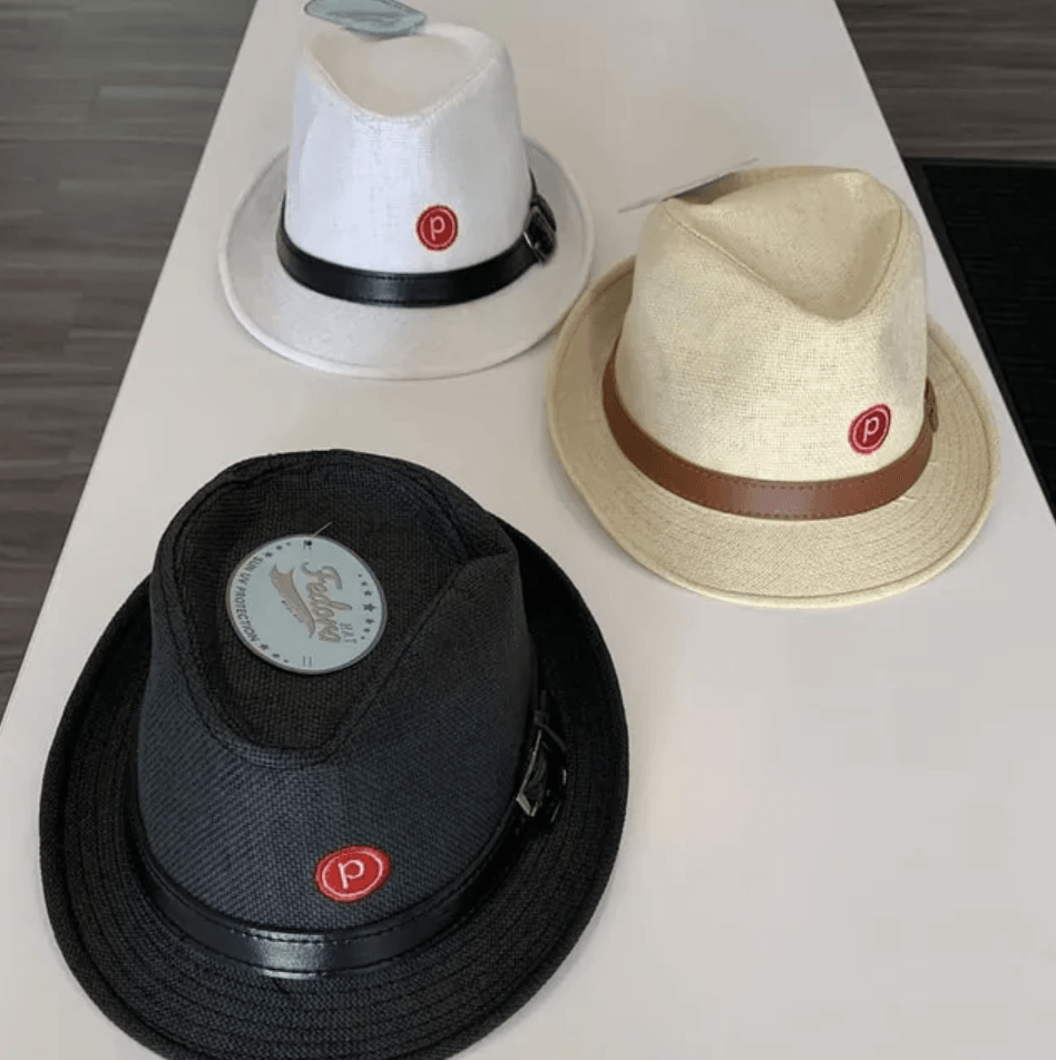 Three hats on a table one of which has the letter p on it