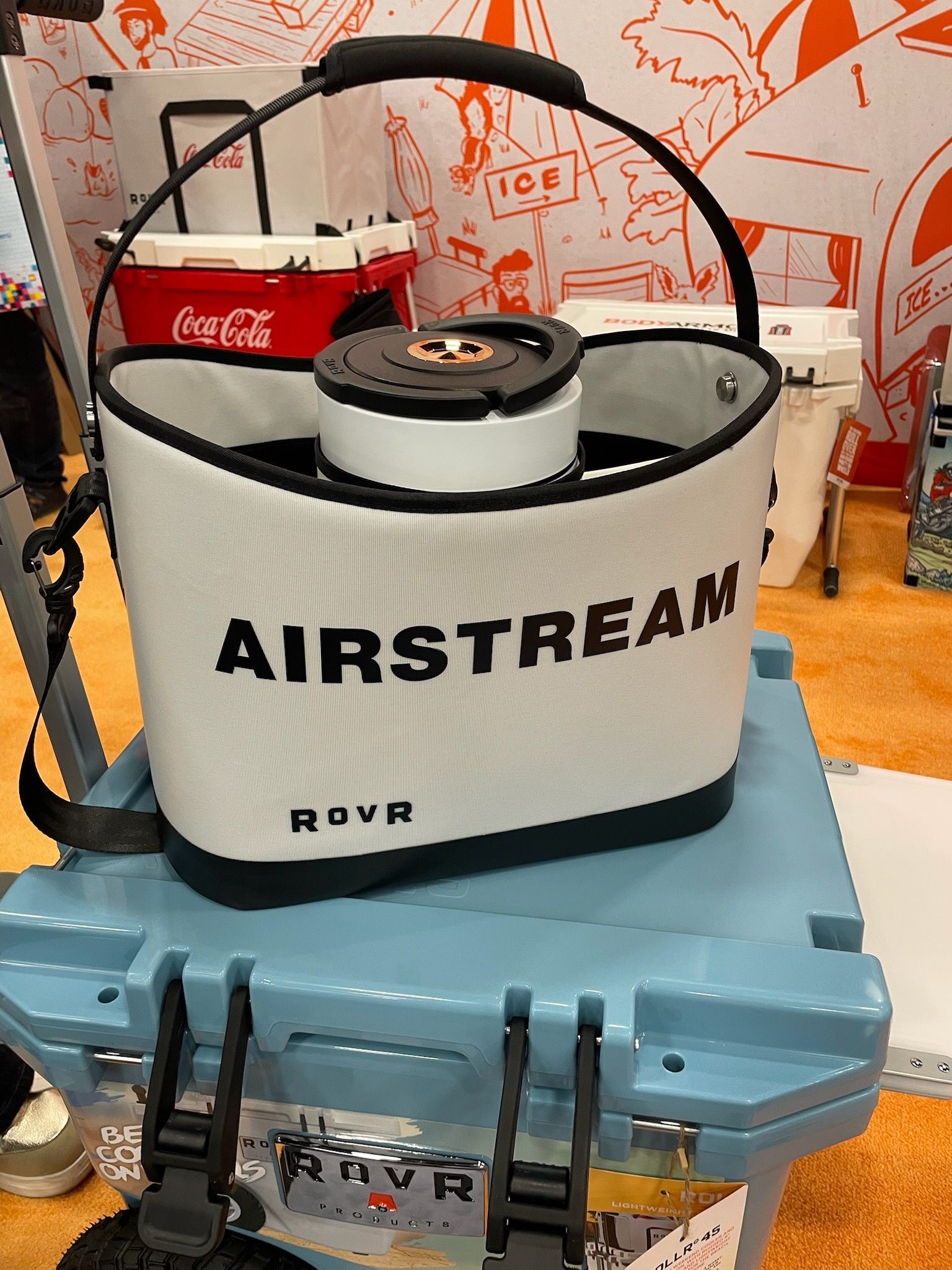 A white airstream cooler is sitting on top of a blue cooler.