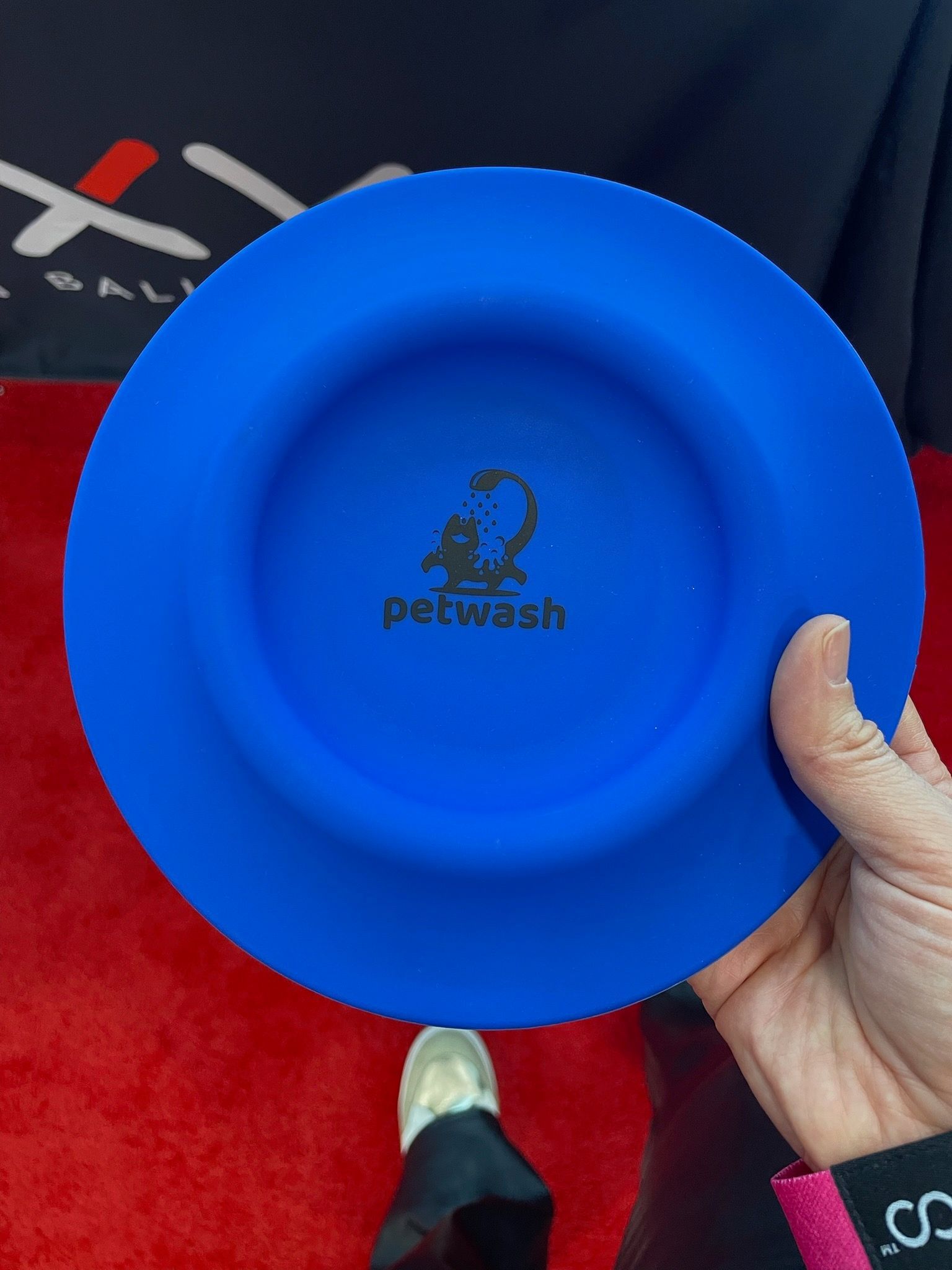 A person is holding a blue plate that says petwash on it