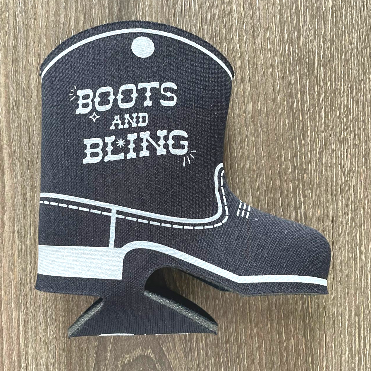 Black cowboy boot ornament with white trim and “BOOTS AND BLING” text on a wood background