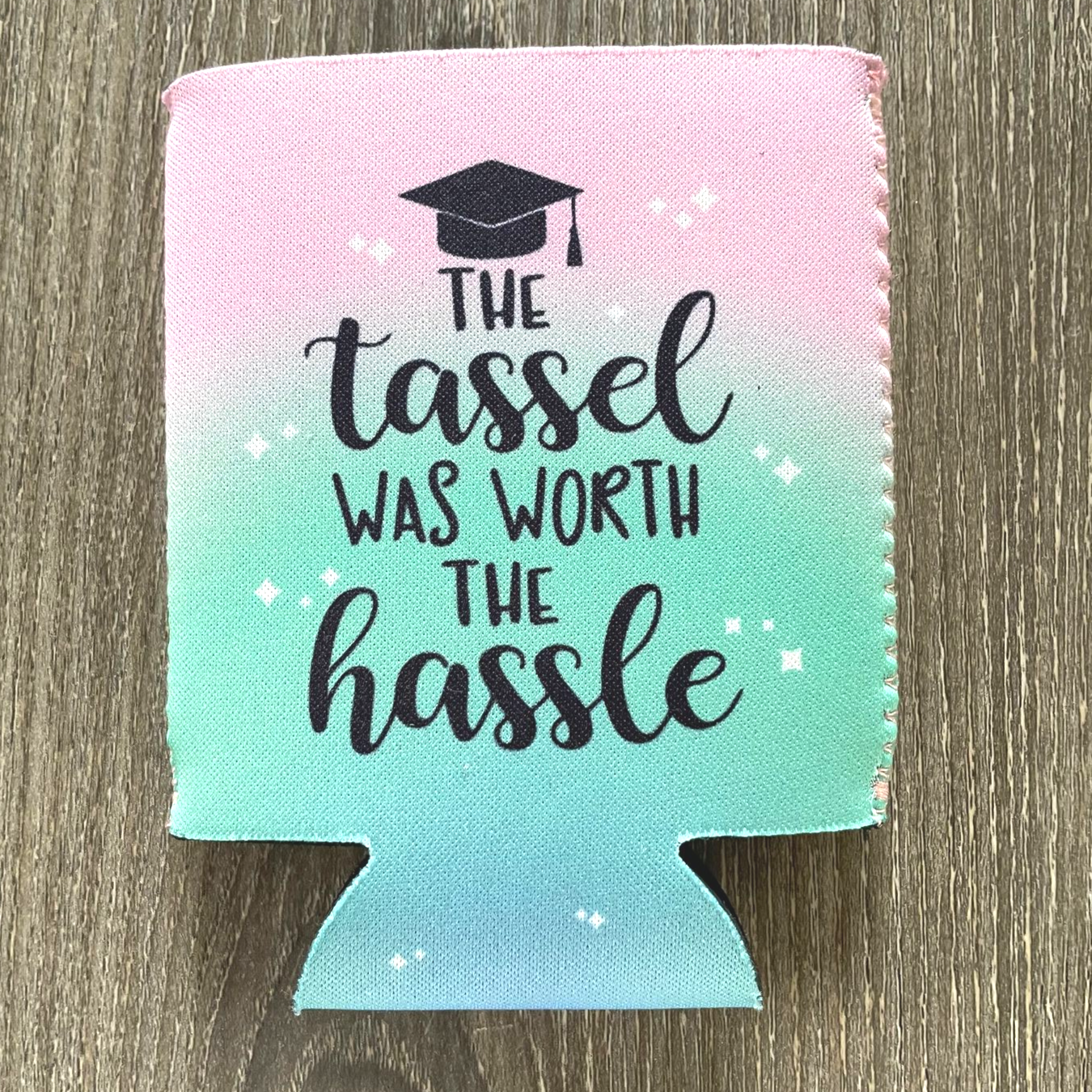 Pink and teal koozie with graduation cap and text, “The tassel was worth the hassle.”