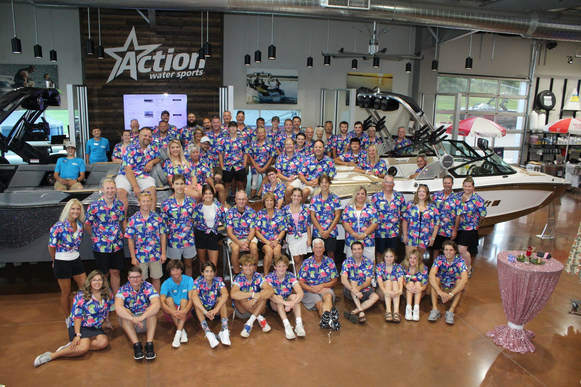 Large group in matching blue jerseys posing indoors with trophies and bowling lanes in the background