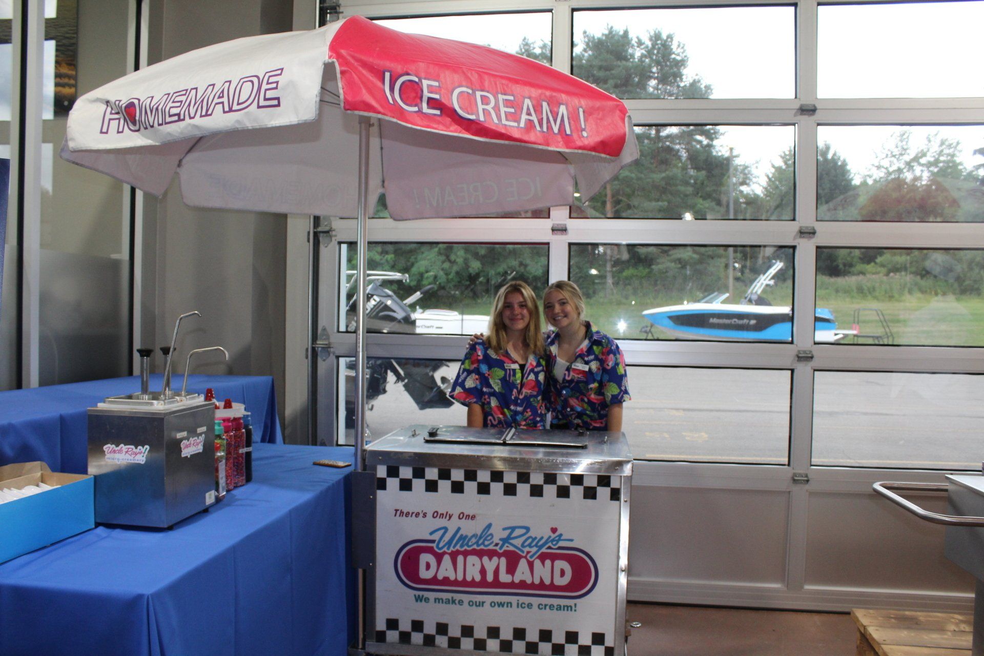 Ice cream stand indoors with two attendants behind a Dairyland counter and pink-and-white umbrella