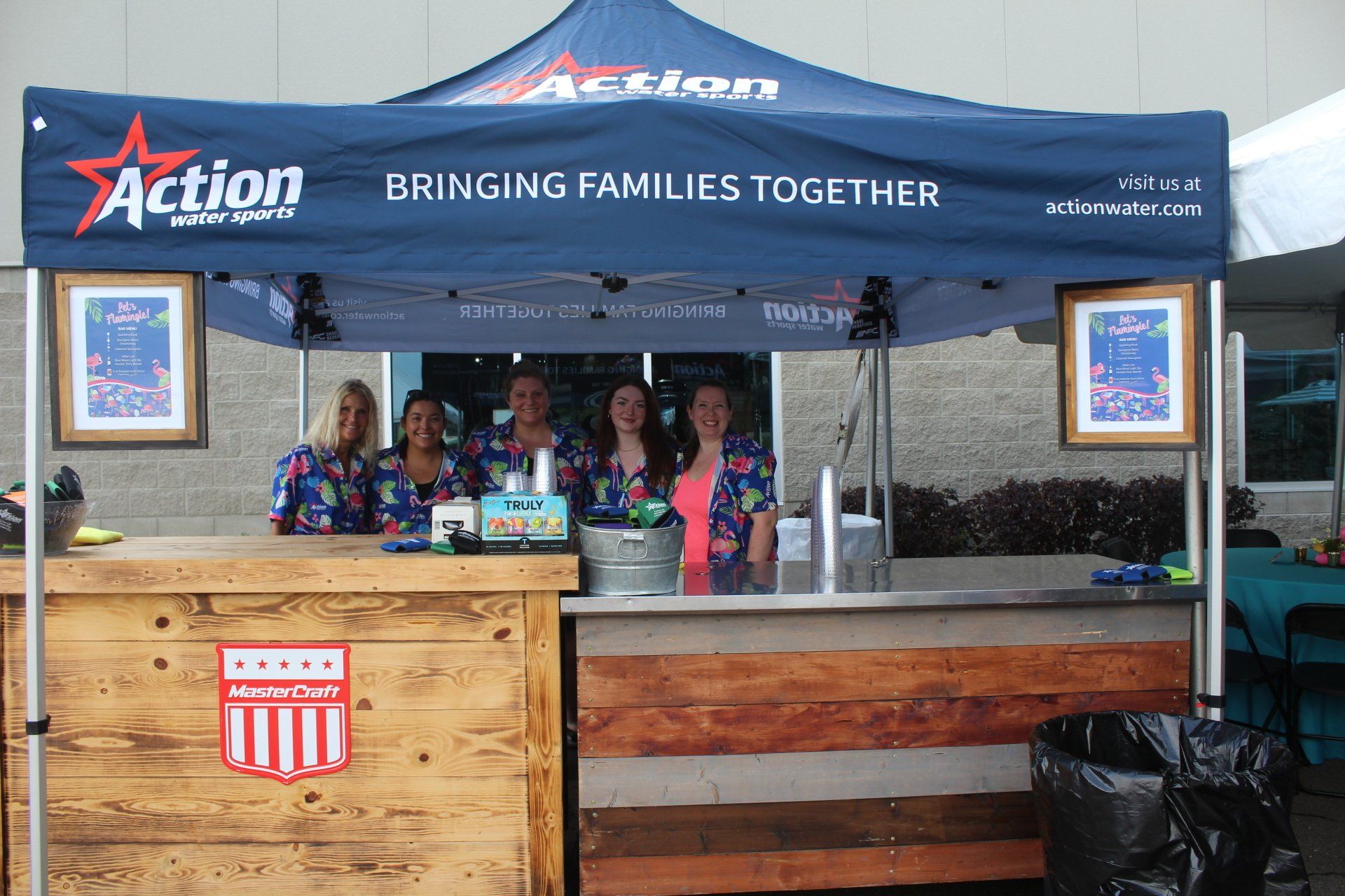 Outdoor Action booth under blue canopy with wooden counter and staff in colorful shirts